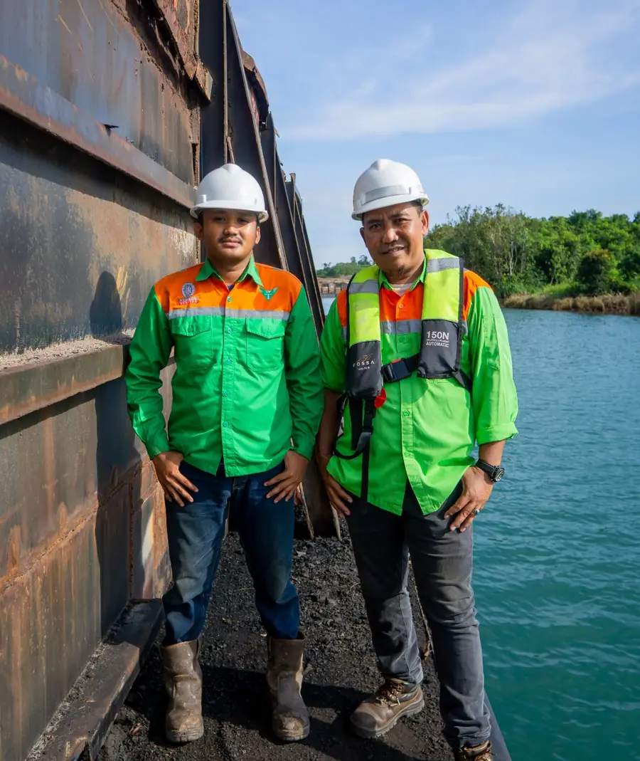 Two Triyasa Hijau surveyors standing beside a coal barge